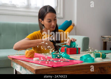 Donna di incarto artigianali fatti a mano doni sul tavolo a casa Foto Stock