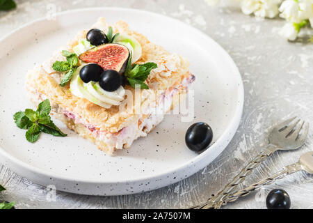 Pavlova su un biscotto con una delicata crema di cagliata, fichi e uva. Una nuova variante del classico dolce Australiano. Foto Stock