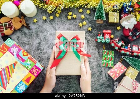 Mano azienda confezione regalo da shopping bag durante la stagione di natale e festival di regali, decorazioni con ornamento di Natale sul tavolo Foto Stock