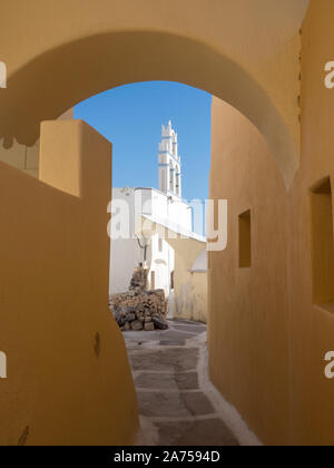 Una vista di una sfumatura ombra back street in epoca medievale città Emborio village alla chiesa cappella orange ocre dipingere le pareti Santorini Foto Stock