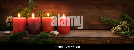 Quarta Domenica di Avvento, la masterizzazione di quattro candele rosse in una fila, Abete rami e decorazione di Natale in scuro legno rustico, ampio formato panoramico con cop Foto Stock