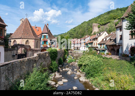 Metà di vecchie case con travi di legno e edifici nella città medievale di Kayserberg sul fiume Weiss, Alsace Francia Foto Stock