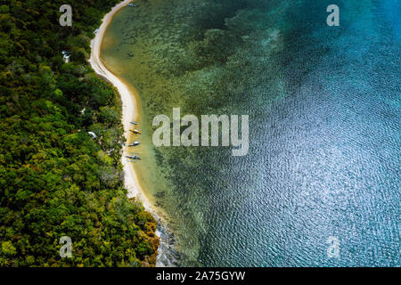 Palawan, Filippine, El Nido. Antenna fuco sopra vista di un appartato deserta spiaggia tropicale con locale barche tradizionali sul litorale di fronte Foto Stock