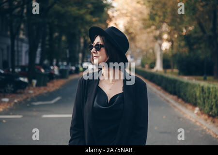 Perfetto autunno 2019 abito moda. european fashion blogger indossando raso di seta top nero, blazer, quadrato di occhiali da sole e un cappello Fedora. street style po Foto Stock