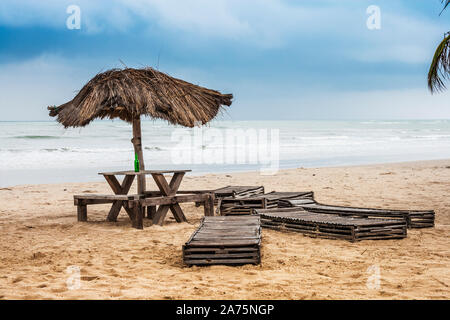 Un vuoto di verde bottiglia di birra a sinistra dietro su una spiaggia deserta in Sanyang, il Gambia. Foto Stock