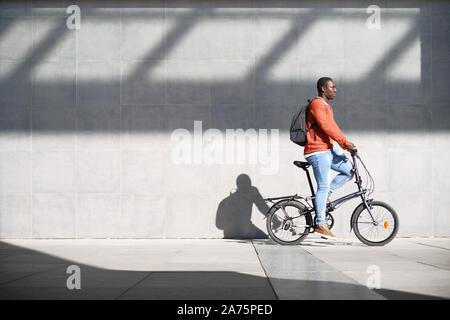 L'uomo africano equitazione Bicicletta pieghevole per gli spostamenti urbani Foto Stock