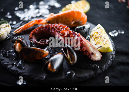 pesce fresco con limone e aglio alla griglia - polpo, gamberi, calamari, conchiglie Foto Stock