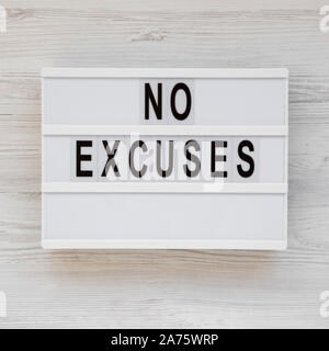 "Scuse" parole su un lightbox su un bianco superficie in legno, vista dall'alto. Overhead, dal di sopra, piatto laici. Foto Stock