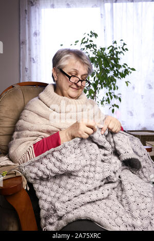 Close-up ritratto di donna Senior Maglia con lana, Nonne Mani di maglia di filo di lana. L'imbarcazione è Hobby delle donne anziane. Senior Lady, Felice Granny Knitte Foto Stock