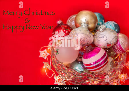Vintage Ornamenti natale in una ciotola di cristallo con auguri di Buon Natale e Felice Anno Nuovo testo Foto Stock