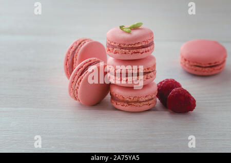 Rosa lampone macarons sulla tavola di legno. Francese dessert amaretti su sfondo bianco. Foto Stock