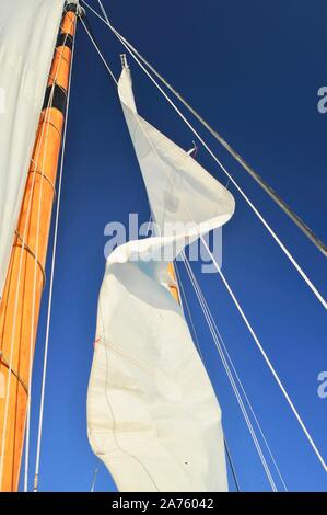 Vele bianche sollevato, il riempimento con il vento, su goletta America 2.0 solcare le acque turchesi durante il tramonto salpare Key West, Florida Keys, Florida, Stati Uniti d'America Foto Stock