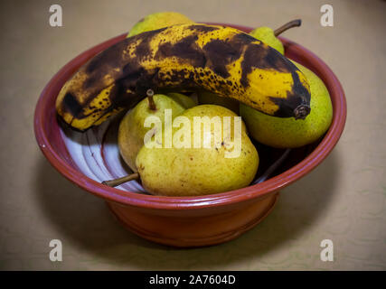 Bartlett pere maturazione in una ciotola con una banana a New York sabato 26 ottobre, 2019. La produzione di gas di etilene dalla banana matura le pere. (© Richard B. Levine) Foto Stock