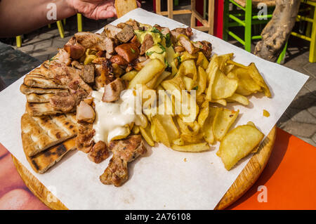 Piatto di carne alla griglia con Patatine fritte e pane pita su una tavola di legno Foto Stock