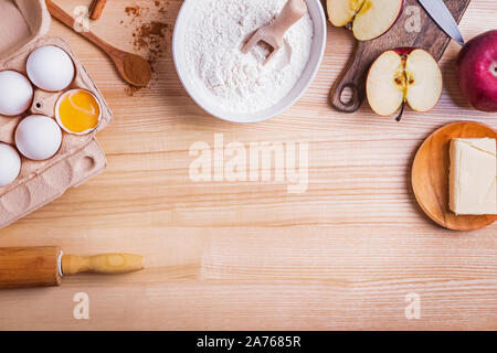 In autunno la cottura. Ingredienti e strumenti per la torta di mele sul tavolo di legno, vista dall'alto. Foto Stock