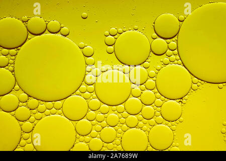 Olio di oliva in una bottiglia di vetro e olive verdi su bianco, vista dall'alto. Foto Stock