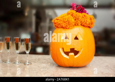 Bicchieri di vino spumante calici, accanto alla zucca di Halloween che è pronto per celebrare il giorno dei morti in Messico venti petali di fiori Foto Stock