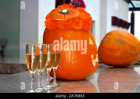 Bicchieri di vino spumante servito in bicchieri, accanto alla zucca di Halloween che è pronto per celebrare il giorno dei morti in Messico Foto Stock