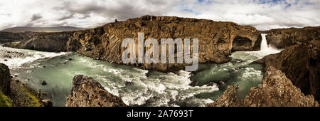 Vista panoramica su un ampio paesaggio, in primo piano una cascata con rapide in enormi massi di basalto, al di sopra di un cielo di contrasto - Islanda, Aldeyjarfoss Foto Stock