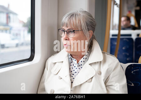 Senior donna seduta sul treno a guardare fuori dalla finestra Foto Stock