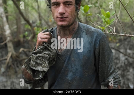 Guaraquecaba, Parana, Brasile - 21 Novembre 2015: Giovani man picking granchi di una mangrovia dall isola Superagui, una comunità di Caicara nel Brasile del Sud Foto Stock