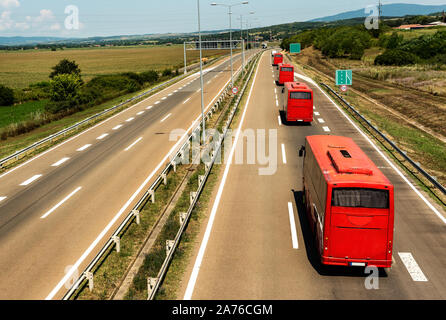 Roulotte o un convoglio di autobus rossi in linea che viaggiano su una autostrada Autostrada del paese Foto Stock