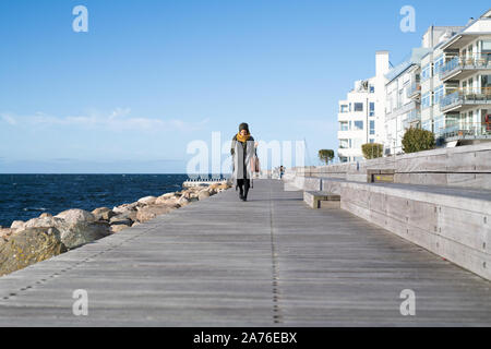 Donna che indossa velo a piedi da Ocean con valigetta Foto Stock