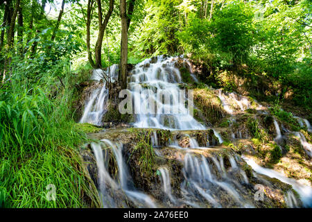 Belle cascate nel villaggio di Donji Taor, vicino a Valjevo, Serbia, Taorska vrela. Piante verdi e moss bloom accanto all'acqua che scorre verso il basso le rocce Foto Stock