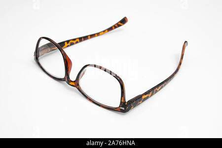 Gli occhiali da lettura guscio di tartaruga pattern isolati su uno sfondo luminoso che giace piatto e capovolto. Primo piano di occhiali. Foto Stock