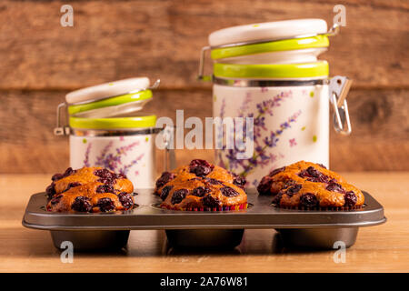 Sei appena sfornato banana-ciliegia muffin su un vassoio di muffin e due vasi di contenitore Foto Stock