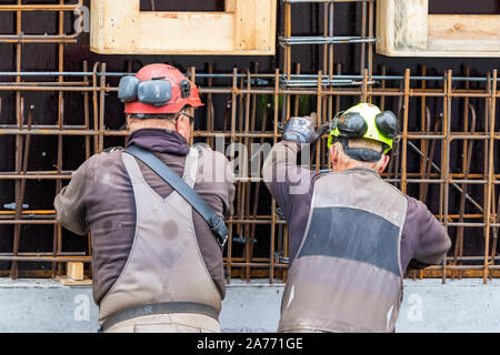 Lavoratori edili piegatura - cablaggio calcestruzzo barre di acciaio all'aperto in Nuuk. Foto Stock