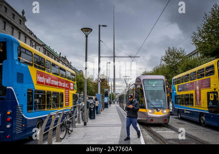 Gli autobus e i tram in O'Connell Street, in background Guglia di Dublino noto anche come un monumento di luce da parte di Ian Ritchie Architects, Dublino, Irlanda Foto Stock