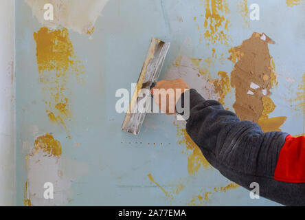 L'uomo lavoratore utilizzando costruttori primo strato di mastice gesso per montaggio a parete Foto Stock