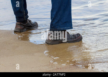 Vista del mans piedi indossando scarpe acqua stagnante. Foto Stock