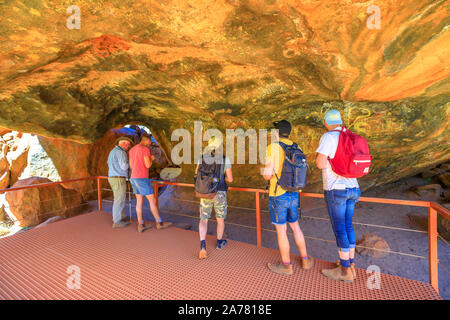 Uluru, Territorio del Nord, Australia - 24 AGO 2019: i turisti alla ricerca di disegni dipinti su roccia nella grotta di Mutitjulu lungo Kuniya a piedi o Kulpi Mutitjulu Foto Stock