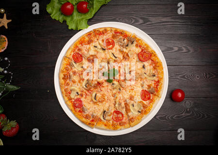 Un assortimento di pizza tagliata in pezzi al buio su un sfondo di legno Foto Stock