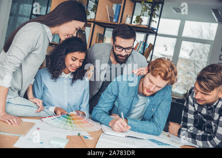 Startupers lavorando insieme a Office seduta guardando alla tavolozza dei colori prendendo appunti felice Foto Stock
