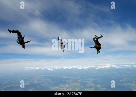 Questi skydivers sono battenti intorno a ogni altro con una velocità elevata nel cielo blu. Ben presto si terranno le mani e costruire una formazione compresi come una squadra. Foto Stock