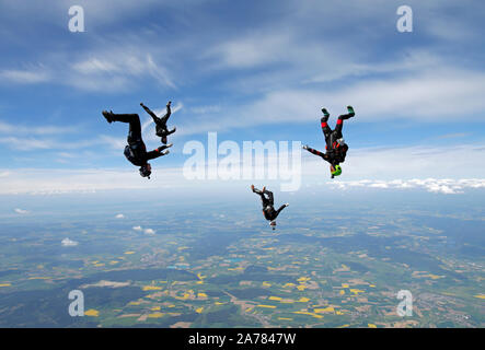 Skydivers stanno avendo divertimento insieme nel cielo e sono battenti intorno a ogni altro con una velocità alta. Presto costruiranno una formazione e tenere le mani. Foto Stock