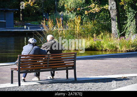 Vecchia coppia seduta su una panchina nel parco nel bosco Foto Stock