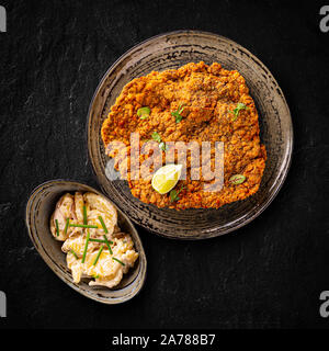 Carne di vitello gigante schnitzel viennesi servito con insalata di patate con erba cipollina Foto Stock