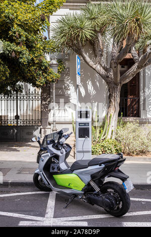 BMW C Evoluzione scooter elettrico, motociclo, inserito in una ricarica Circutor punto su una strada a Santa Cruz de Tenerife, Isole Canarie, Spagna Foto Stock