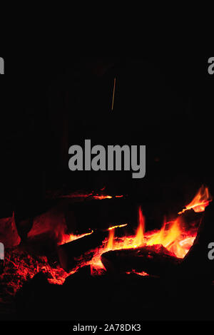 Un fuoco che brucia in un camino a notte oscura, verticale dello sfondo della foto Foto Stock