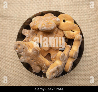 Gingerbreads di varie forme in un recipiente di metallo posto su una tovaglia Foto Stock