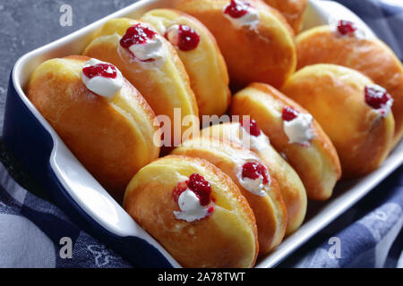 Berliner Pfannkuchen, Tedesco Ciambelle con marmellata di lamponi e ripieni di crema in una teglia su una tabella di calcestruzzo Foto Stock