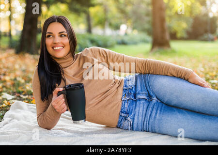 Bella donna di bere il caffè mentre gode in autunno nel parco. Foto Stock