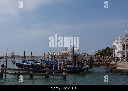 Acqua tradizionali scena di Venezia con molte gondole attraccate in alto tra i poli. Grandi cieli sopra al sole. Foto Stock