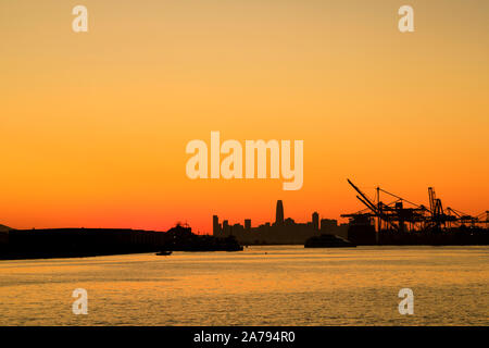 Tramonta sullo skyline di San Francisco e sulle gru pesanti Oakland Port, Oakland, California Foto Stock