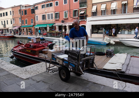Uomo di consegna con carrello carico di Murano, Venezia. N. veicoli ammessi, così tutto è consegnato a mano da la chiatta - non importa quanto sia pesante e ingombrante. Foto Stock