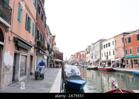 Uomo di consegna con carrello carico di Murano, Venezia. N. veicoli ammessi, così tutto è consegnato a mano da la chiatta - non importa quanto sia pesante e ingombrante. Foto Stock